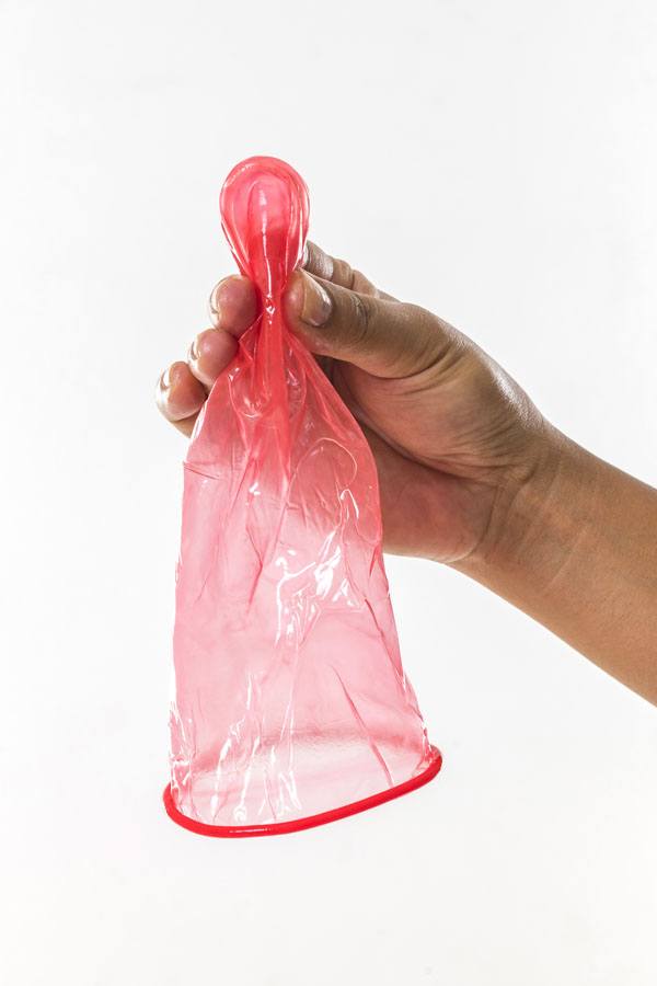 FC2 Female Condom, held by hand, red